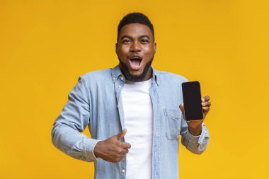 Şaşırmış Afrikalı bir adam akıllı telefon tutuyor ve parmağını kaldırıyor.