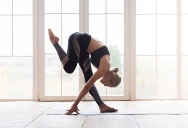 Genç yoga kadını dizine alnıyla dokunuyor.