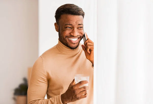 Afro Guy μιλώντας στο τηλέφωνο πίνοντας καφέ στέκεται στο σπίτι — Φωτογραφία Αρχείου