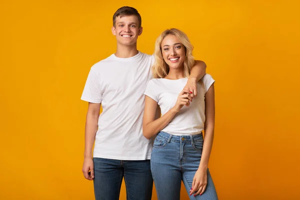 Portrait de couple heureux millénaire câlins sur fond de studio jaune — Photo