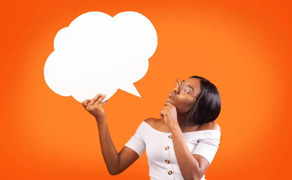 Joven mujer negra sosteniendo discurso burbuja de pie, fondo naranja, burla —  Fotos de Stock