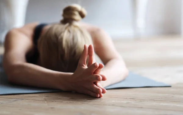 Подходящая девушка ложится лицом на коврик для йоги, растягиваясь — стоковое фото