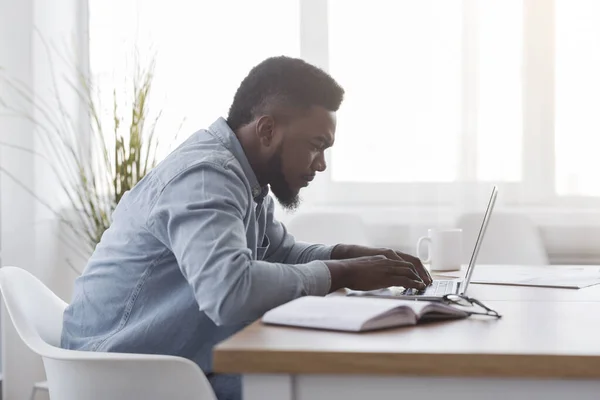 Koncentrerad afrikansk amerikansk chef arbetar på bärbar dator på kontoret — Stockfoto