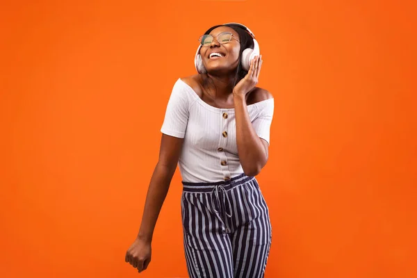 Girl In Headphones Listening to Music Dancing Over Orange Background — стоковое фото
