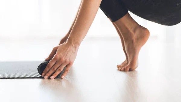 Yoga-Konzept. Frau rollt Yogamatte nach dem Training auf — Stockfoto