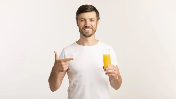 Uomo che tiene il dito di puntamento al succo d'arancia in piedi, studio, panorama — Foto Stock