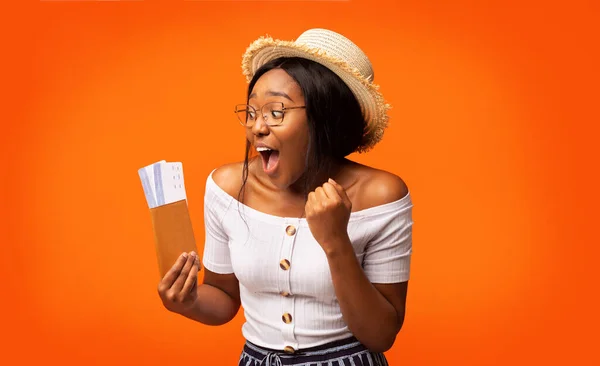 Задоволена чорна жінка тримає квитки і паспорт стоячи, помаранчеве тло — стокове фото