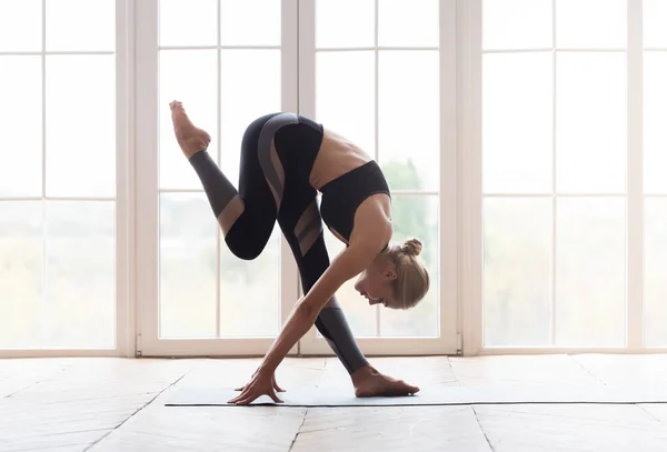 Junge Yoga-Frau berührt ihr Knie mit der Stirn — Stockfoto