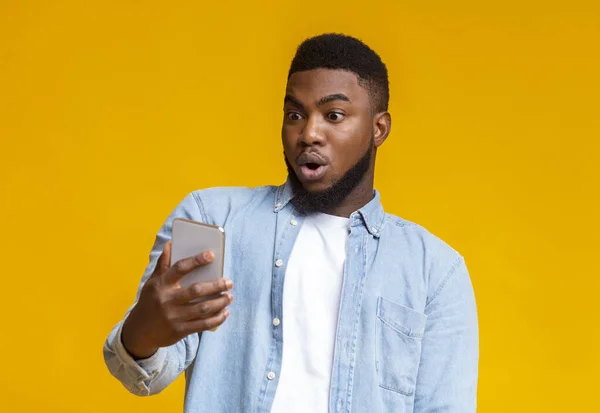 Meglepett afrikai férfi néz smartphone képernyő szájjal nyitott — Stock Fotó