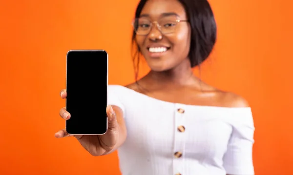 携帯電話の空の画面立ち、オレンジの背景、モックアップを示す黒の女の子 — ストック写真