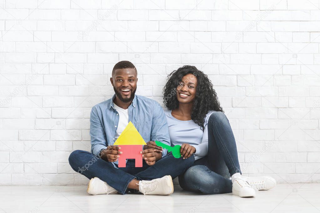 African couple holding colorful plastic house and key