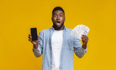 Siyah ekran ve dolar nakitle cep telefonu tutan Afro adam.