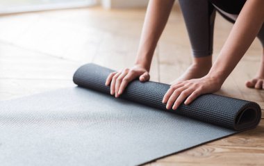 Antrenmandan önce yoga minderini açan kadının elleri