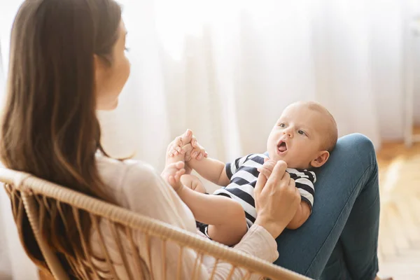 Söt liten bebis ligger på mammor knä och cooing — Stockfoto