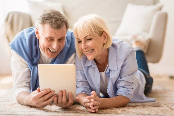 Vzrušený starší pár procházející sociální média na tabletu — Stock fotografie