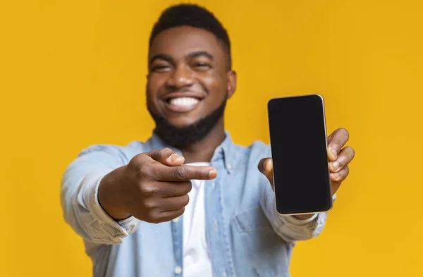 Cara africano alegre apontando para smartphone com tela preta — Fotografia de Stock