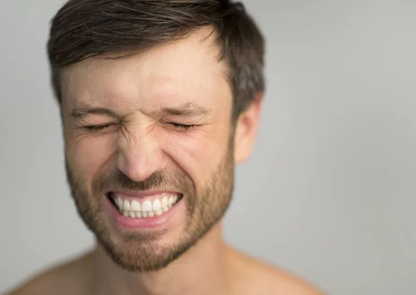 Muž se zavřenýma očima Usmívající se přes šedé studio na pozadí — Stock fotografie