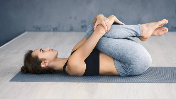 Mulher praticando ioga, deitado de joelhos para pose no peito — Fotografia de Stock
