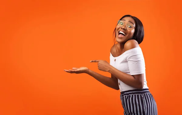 Excited Girl Pointing Finger At Open Palm Standing, Orange Background — Stock Photo, Image