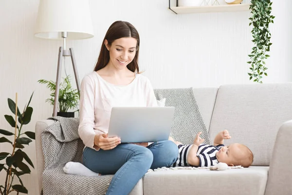 Hermosa madre joven leyendo blog bebé en el ordenador portátil — Foto de Stock