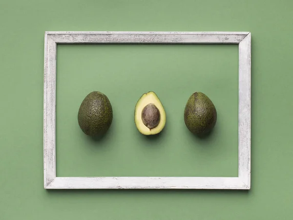 Avocado binnen houten rand in minimalistische stijl op groen — Stockfoto