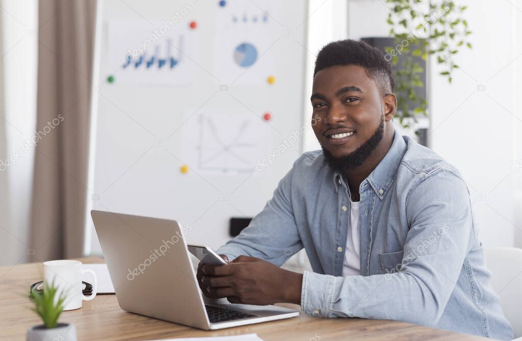 Portrait of confident millennial african american businessman sitting in office
