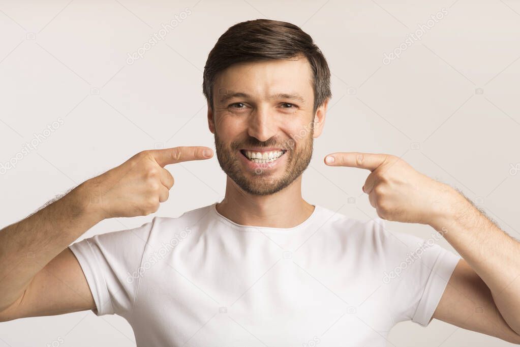 Man Pointing Fingers At His Smile Standing Over White Background