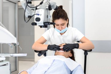 Dişçi kadın doktor, hastasını diş ameliyatından önce hazırlıyor.