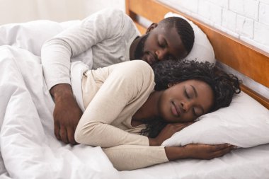 Genç Afro-Amerikan çift yatakta birlikte kestiriyorlar.