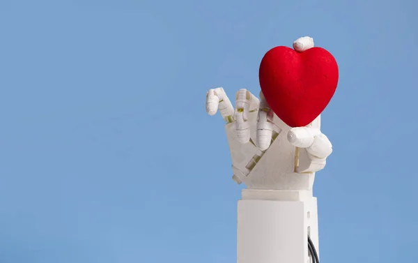 Automated hand of robot doctor holding red heart