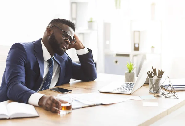 Joven empresario estresado bebiendo whisky en el lugar de trabajo —  Fotos de Stock