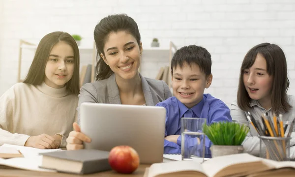 Niños y maestras mirando en la tableta en la lección —  Fotos de Stock