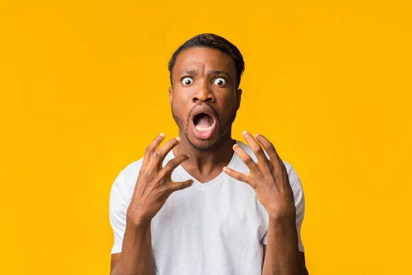 Przerażony czarny człowiek krzyczy patrząc na kamerę stojącą w studio — Zdjęcie stockowe