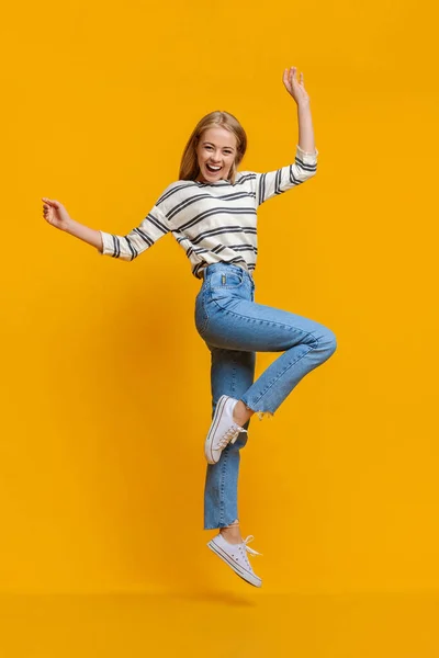 Положительная красивая девочка-подросток, прыгающая в воздух с поднятыми руками — стоковое фото