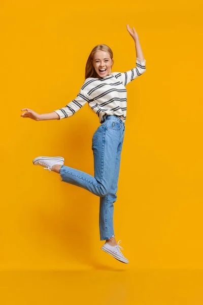 Menina adolescente se divertindo, pulando no fundo do estúdio laranja — Fotografia de Stock