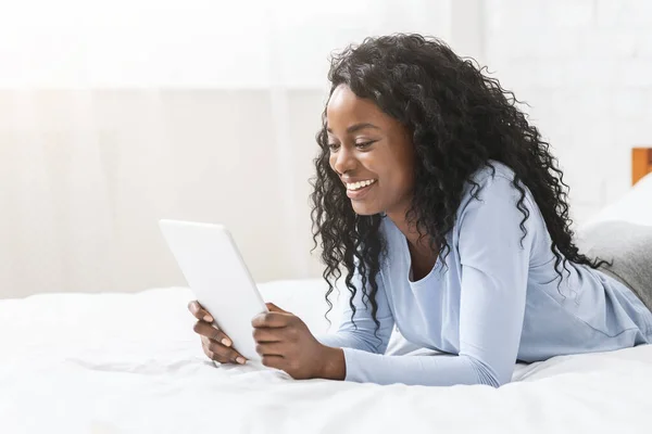 Chica leyendo blog en la tableta digital en la cama —  Fotos de Stock