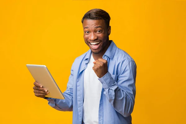 Alegre chico afroamericano sosteniendo la tableta Gestos Sí, Studio Shot — Foto de Stock