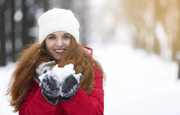 Feliz joven mujer sosteniendo nieve en sus manos —  Fotos de Stock