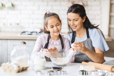 Küçük kız ve güzel annesi birlikte yemek yaparken eğleniyorlar.