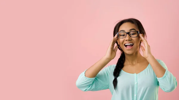 Izgalmas lány megható szemüveg és mosolygós kamera, rózsaszín háttér — Stock Fotó