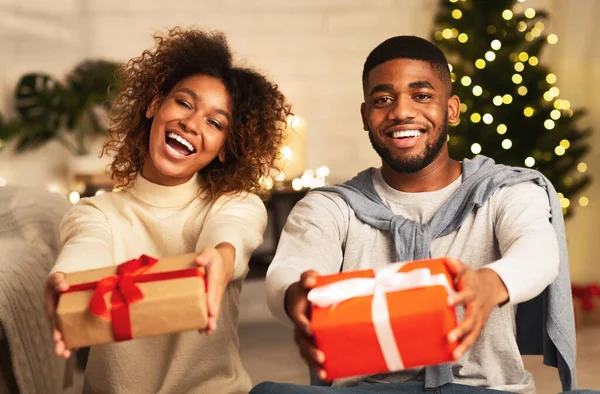 Siyah bir çift Noel hediyesi kutularını tutuyor ve gülümsüyor. — Stok fotoğraf