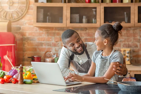 Усміхнений тато і дочка шукають смачний рецепт, використовуючи ноутбук — стокове фото