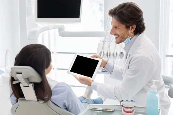 Médico dentista que muestra la pantalla del comprimido digital en blanco del paciente — Foto de Stock