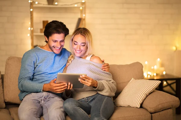 Young couple watching movie on tablet, enjoying cozy evening — ストック写真