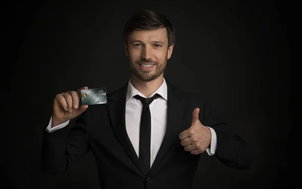 Businessman Holding Credit Card Gesturing Thumbs Up, Black Background — Stock Photo, Image