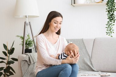 Mutlu anne yeni doğmuş bebeğiyle evde vakit geçiriyor.