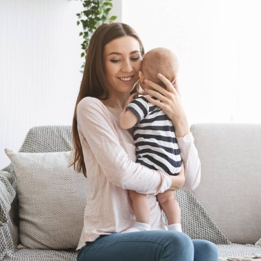 Mutlu genç anne yeni doğmuş bebeği elinde tutuyor.