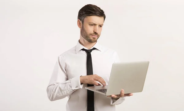 Serieuze zakenman werken aan laptop staande, Studio Shot — Stockfoto