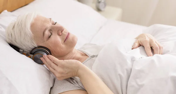 Spokojny senior kobieta w słuchawki korzystających audiobook — Zdjęcie stockowe