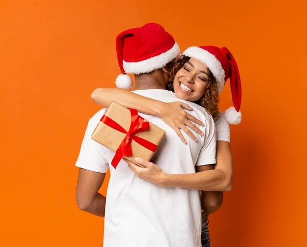 Couple millénaire noir avec cadeau de Noël sur fond orange — Photo